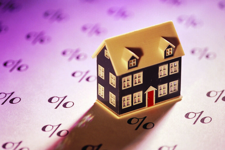 Miniature home on sheet of percent signs