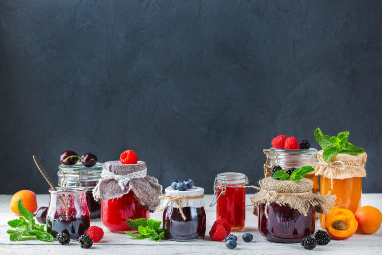 Food and drink, harvest summer autumn concept. Assortment of seasonal berries and fruits jams in jars on a wooden table. Copy space rustic background