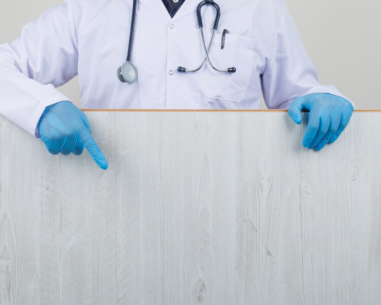 Doctor showing wooden board in white coat, gloves front view.