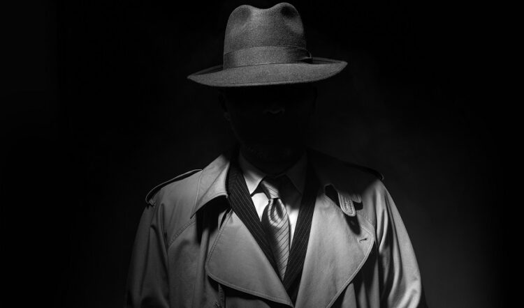 Man posing in the dark with a fedora hat and a trench coat, 1950s noir film style character