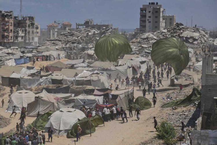 Palestinians rush to collect humanitarian aid airdropped by parachutes into Gaza City, northern Gaza Strip, Thursday, Aug. 7, 2025. (AP Photo/Jehad Alshrafi)